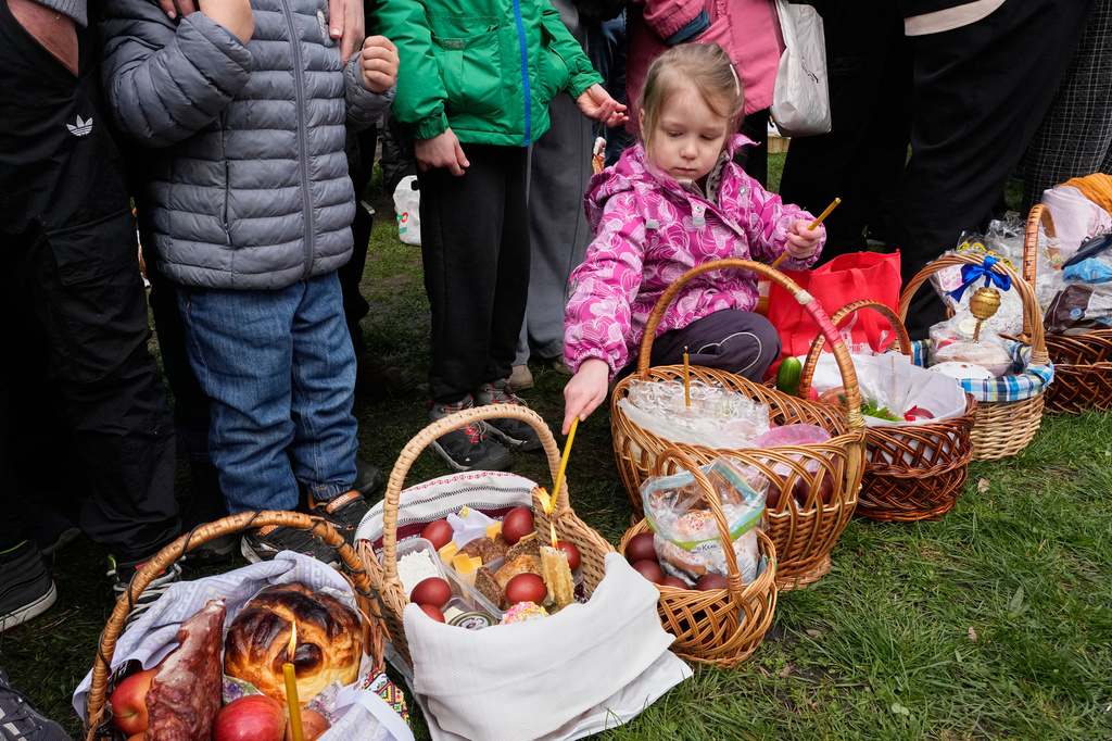 A little girl lights a candle as people bless their Easter baskets to mark Orthodox Easter, in Pyrohiv, close to Kyiv, Ukraine, Sunday, April 12, 2026. (AP Photo/Efrem Lukatsky)