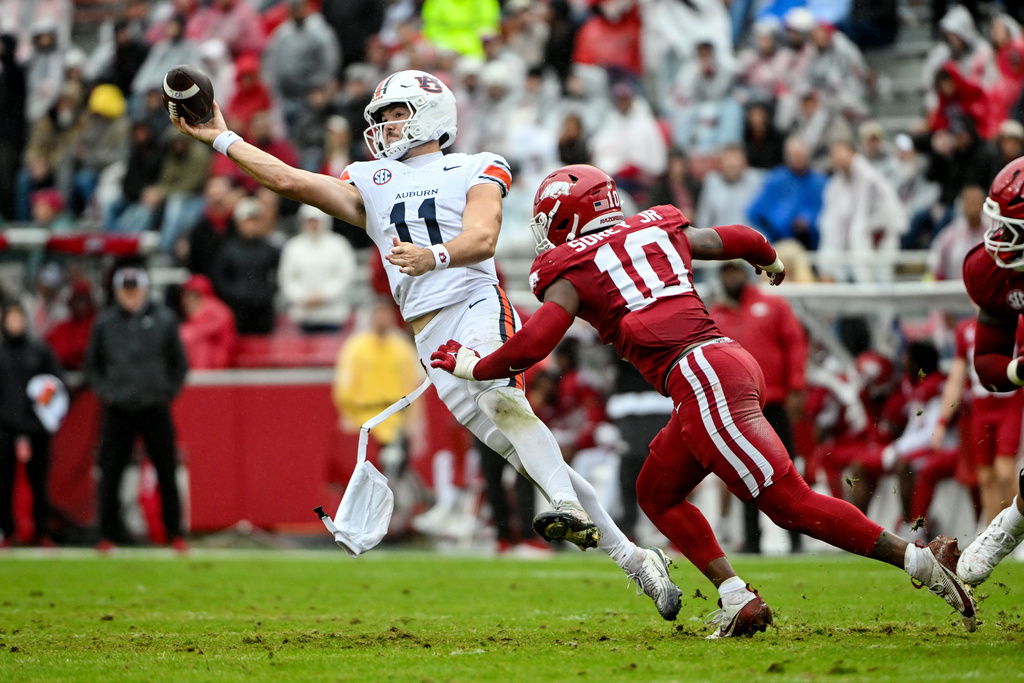 Auburn quarterback Jackson Arnold (11) throws a pass under pressure from Arkansas linebacker Xavian Sorey Jr. (10) during the first half of an NCAA college football game Saturday, Oct. 25, 2025, in Fayetteville, Ark. (AP Photo/Michael Woods)