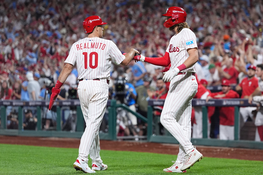 Philadelphia Phillies' J.T. Realmuto, left, and Alec Bohm celebrate after scoring off a double hit by Nick Castellanos during the ninth inning in Game 2 of baseball's National League Division Series against the Los Angeles Dodgers, Monday, Oct. 6, 2025, in Philadelphia. (AP Photo/Matt Rourke)