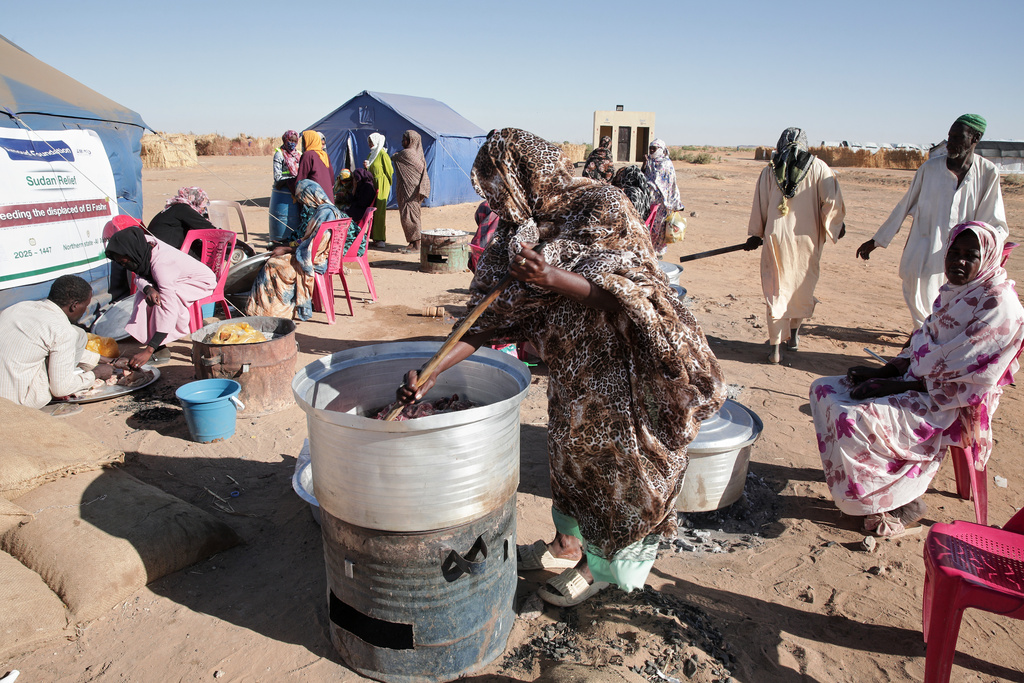 Sudanese women displaced from El-Fasher cook meals at a community kitchen inside the newly established El-Afadh camp in Al Dabbah, in Sudan's Northern State, Sunday, Nov. 16, 2025. (AP Photo/Marwan Ali)