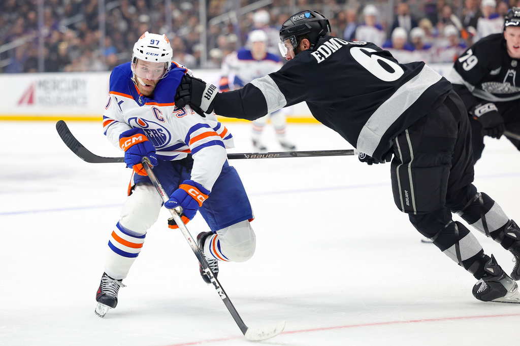 Edmonton Oilers center Connor McDavid, left, moves the puck against Los Angeles Kings defenseman Joel Edmundson, right, during the first period of an NHL hockey game Saturday, April 11, 2026, in Los Angeles. (AP Photo/Ryan Sun)