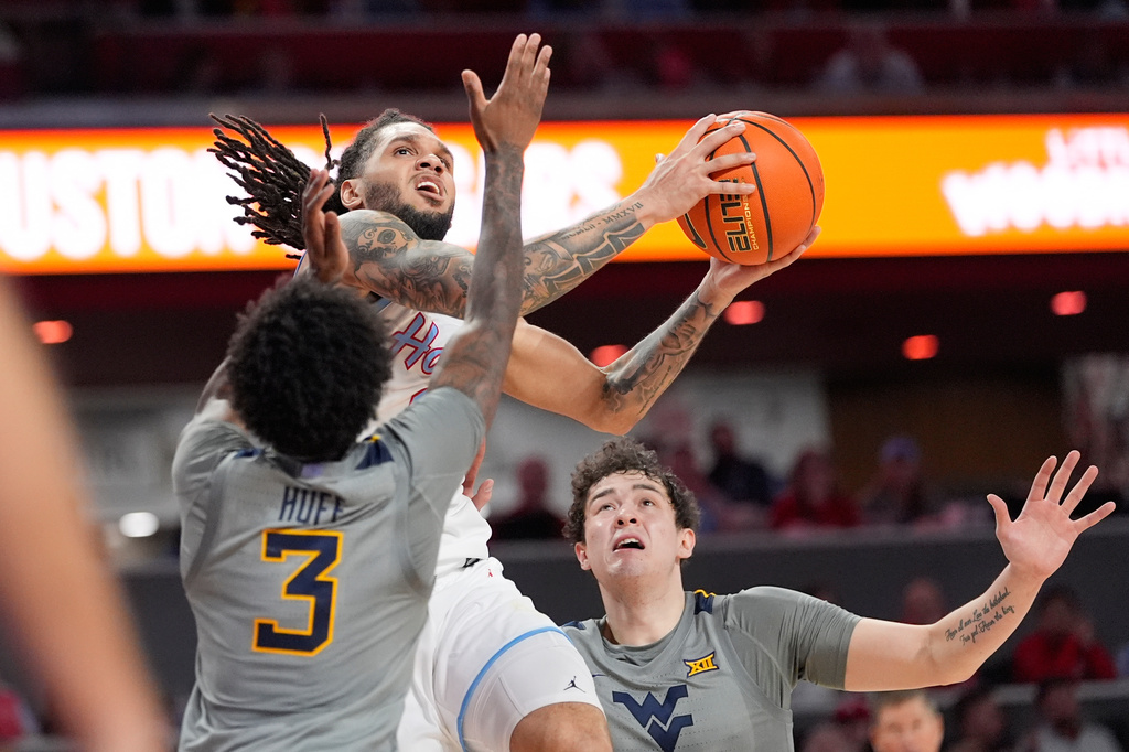 Houston's Emanuel Sharp, center, goes up for a shot as West Virginia's Honor Huff (3) and Treysen Eaglestaff (52) defend during the second half of an NCAA college basketball game Tuesday, Jan. 13, 2026, in Houston. (AP Photo/David J. Phillip)