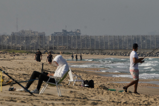 Backdropped by buildings destroyed during Israeli ground and air operations in the northern Gaza Strip, people walk and fish at Zikim Beach, near Ashkelon, in southern Israel, Friday, Oct. 17, 2025. (AP Photo/Leo Correa) Backdropped by buildings destroyed during Israeli ground and air operations in the northern Gaza Strip, people walk and fish at Zikim Beach, near Ashkelon, in southern Israel, Friday, Oct. 17, 2025. (AP Photo/Leo Correa)
