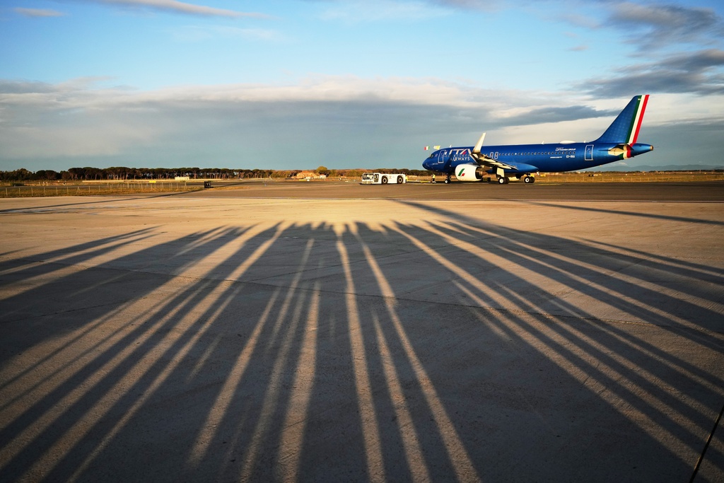 Reporters' shadows are cast on the tarmac as they wait for the plane to depart that is transporting Pope Leo XIV to a six-day trip to Turkey and Lebanon, at the Fiumicino airport in Rome, Thursday, Nov. 27, 2025. (AP Photo/Alessandra Tarantino)