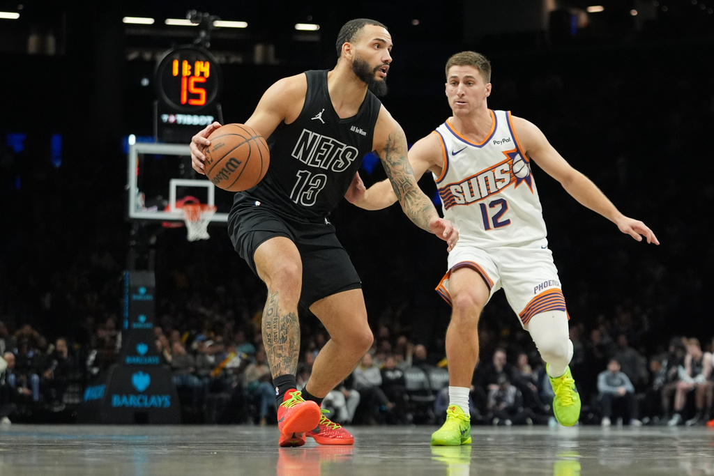 Phoenix Suns' Collin Gillespie (12) defends Brooklyn Nets' Tyrese Martin (13) during the second half of an NBA basketball game Monday, Jan. 19, 2026, in New York. (AP Photo/Frank Franklin II)