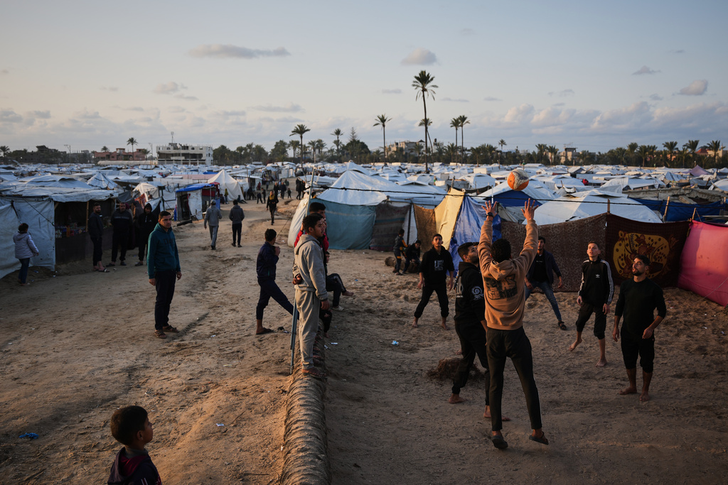 Young Palestinians play volleyball at a tent camp sheltering displaced families in Deir al-Balah, in the central Gaza Strip Tuesday, Jan. 20, 2026. (AP Photo/Abdel Kareem Hana)
