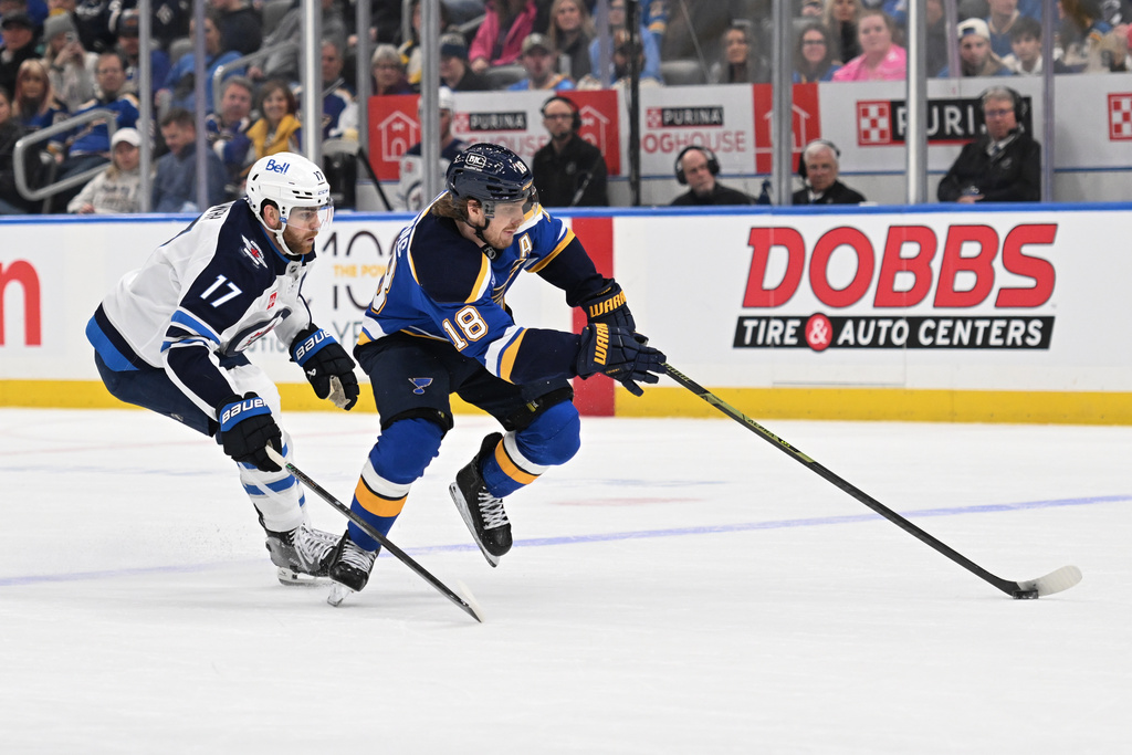 Winnipeg Jets center Adam Lowry (17), left, pressures St. Louis Blues center Robert Thomas (18) during the second period of an NHL hockey game on Wednesday, Dec. 17, 2025, in St. Louis. (AP Photo/Joe Puetz)