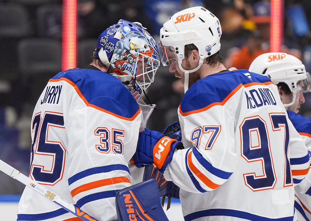 Edmonton Oilers goalie Tristan Jarry (35) and Connor McDavid (97) celebrate after Edmonton defeated the Vancouver Canucks 6-0 during an NHL hockey game, in Vancouver, on Saturday, Jan. 17, 2026. (Darryl Dyck/The Canadian Press via AP)