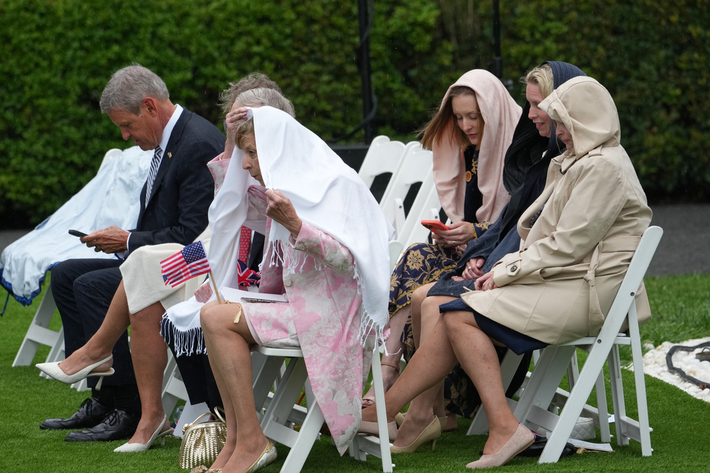 Guests arrive in the rain before President Donald Trump and first lady Melania Trump greet Britain's King Charles III and Queen Camilla during a State Visit arrival ceremony on the South Lawn of the White House, Tuesday, April 28, 2026, in Washington. (AP Photo/Alex Brandon)
