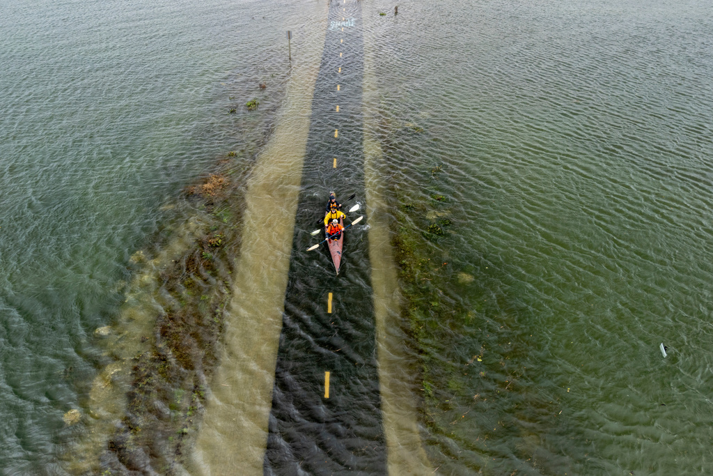 From front, brothers Connor and Brett Cardinal, and friend Eli Ferrell kyak through a flooded Mill Valley-Sausalito Path during king tide in Mill Valley, Calif., Saturday, Jan. 3, 2026. (Stephen Lam /San Francisco Chronicle via AP)