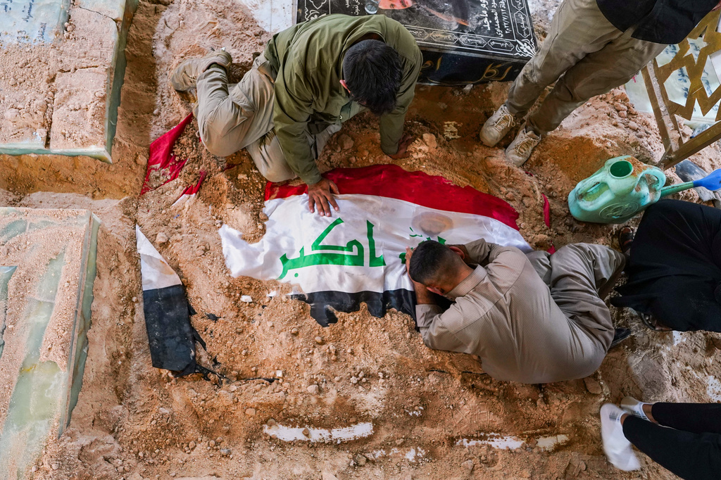 Mourners grieve at the grave of a Popular Mobilization Forces fighter during a funeral for fighters killed in airstrikes on PMF bases in Najaf, Iraq, Thursday, July 30, 2026. (AP Photo/Anmar Khalil)