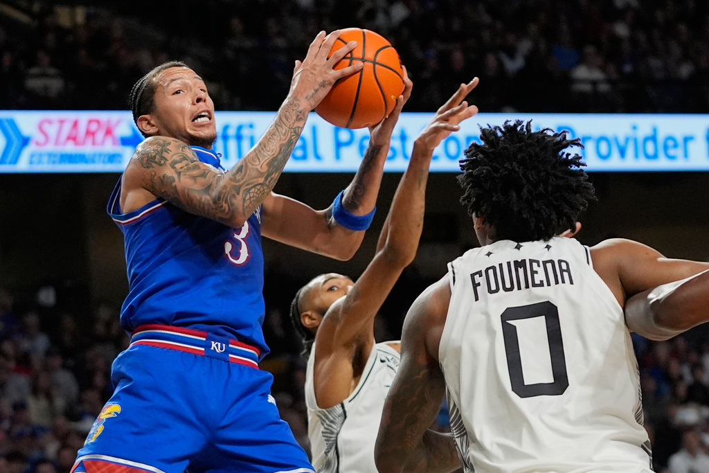 Kansas guard Tre White (3) grabs a rebound in front of Central Florida forward Jordan Burks, back center, and center Jeremy Foumena (0) during the first half of an NCAA college basketball game, Saturday, Jan. 3, 2026, in Orlando, Fla. (AP Photo/John Raoux)