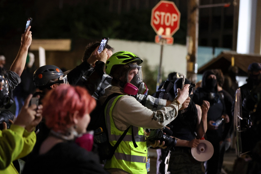 People film as federal agents walk into the street during a protest outside a U.S. Immigration and Customs Enforcement facility in Portland, Oregon, Friday, Oct. 3, 2025. (AP Photo/Amanda Loman)