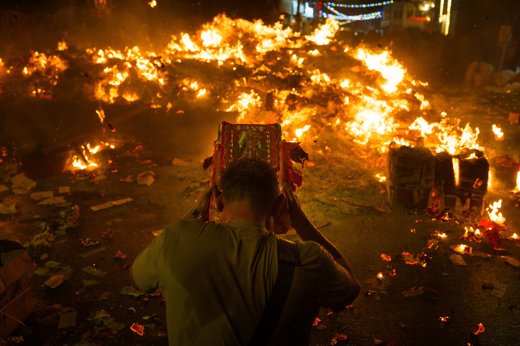 An ethnic Chinese devotee throws paper offerings into a fire during the Hungry Ghost Festival in Bukit Metajam, Malaysia, Saturday, Aug. 29, 2026. (AP Photo/Vincent Thian)