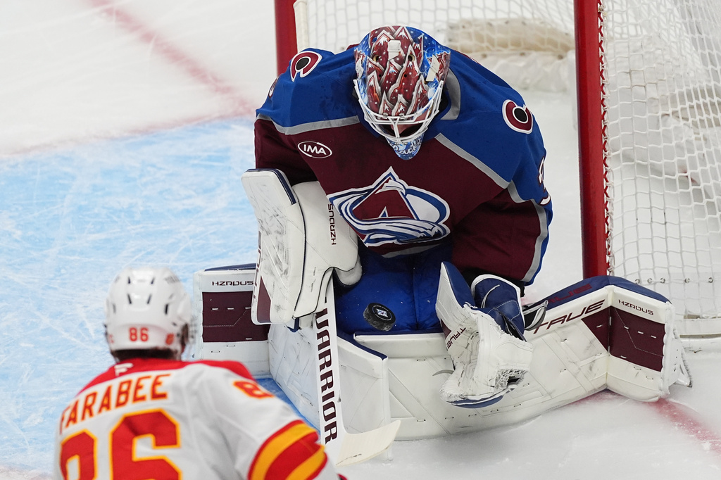 Calgary Flames left wing Joel Farabee, front, puts a shot on Colorado Avalanche goaltender MacKenzie Blackwood in the first period of an NHL hockey game Thursday, April 9, 2026, in Denver. (AP Photo/David Zalubowski)