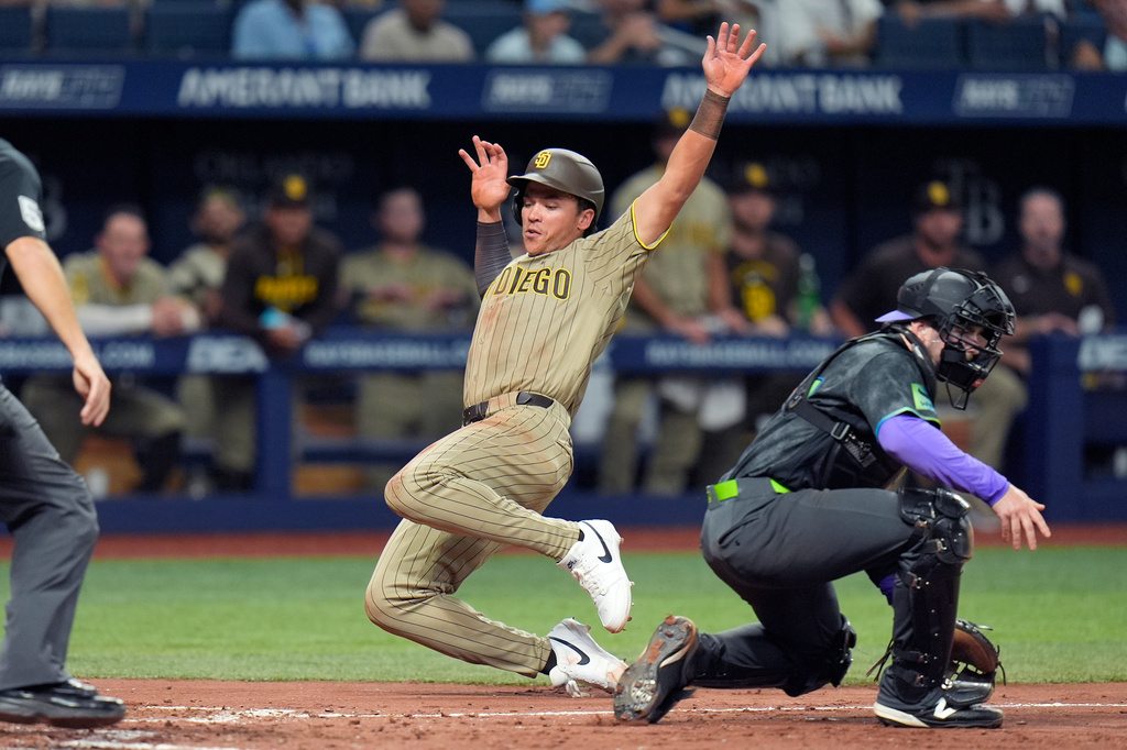 San Diego Padres' Dustin Harris, left, scores past Tampa Bay Rays catcher Liam Hicks on a two-run single by Manny Machado during the seventh inning of a baseball game Saturday, Aug. 29, 2026, in St. Petersburg, Fla. (AP Photo/Chris O'Meara)