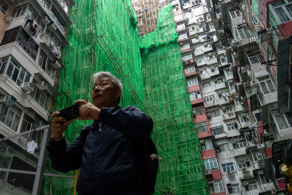 People walk past the building under renovation in Quarry Bay district after the deadly fire at Wang Fuk Court, in the Tai Po district of Hong Kong's New Territories, Thursday, Dec 4, 2025. (AP Photo/Chan Long Hei)