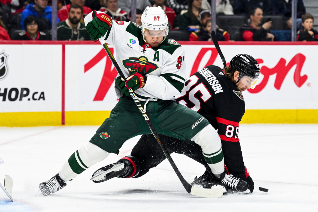 Minnesota Wild's Kirill Kaprizov (97) fights to maintain his balance as Ottawa Senators' Jake Sanderson (85) falls to the ice while chasing the puck during the first period of an NHL hockey game, Saturday, April 4, 2026, in Ottawa, Ontario. (Spencer Colby/The Canadian Press via AP)