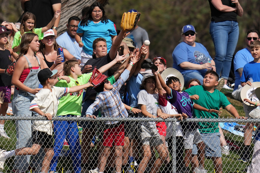 Fans reach for a baseball tossed into the crowd by Los Angeles Angels center fielder Mike Trout during the fourth inning of a spring training baseball game against the San Diego Padres Tuesday, March 10, 2026, in Tempe, Ariz. (AP Photo/Ross D. Franklin)