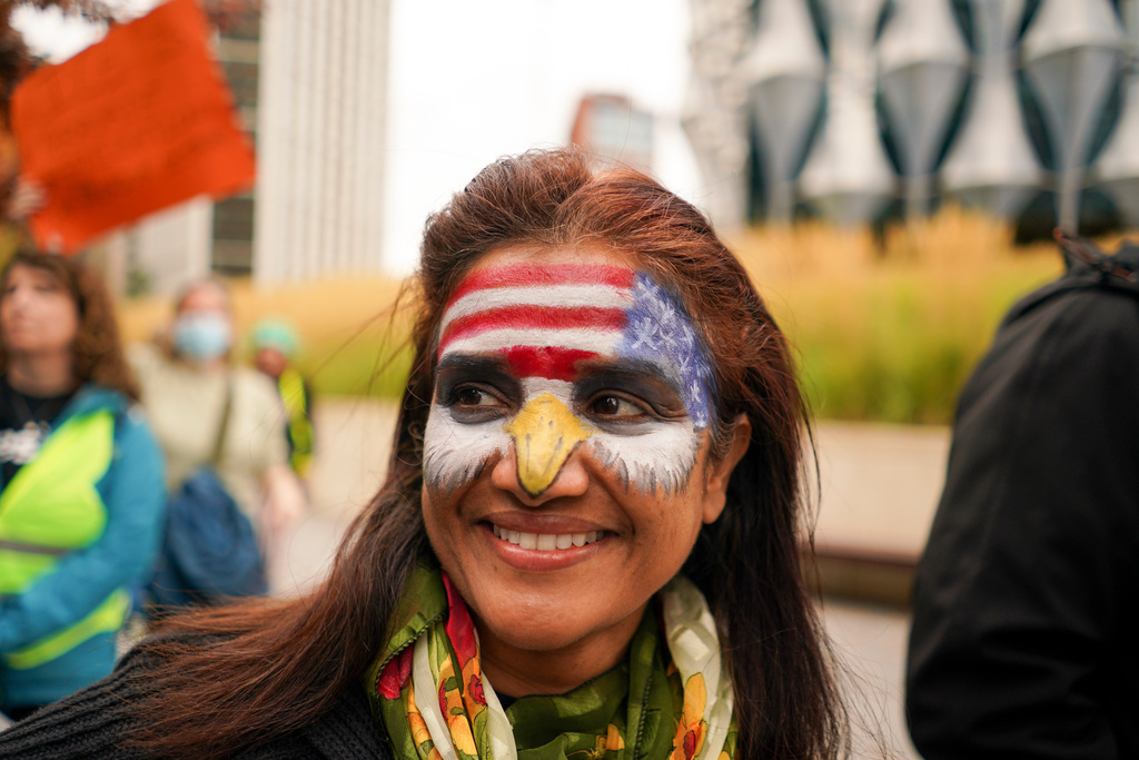 A demonstrator has her face painted with a U.S. flag as she attends a protest outside the U.S. embassy, in London, Saturday, Oct. 18, 2025.(AP Photo/Alberto Pezzali)