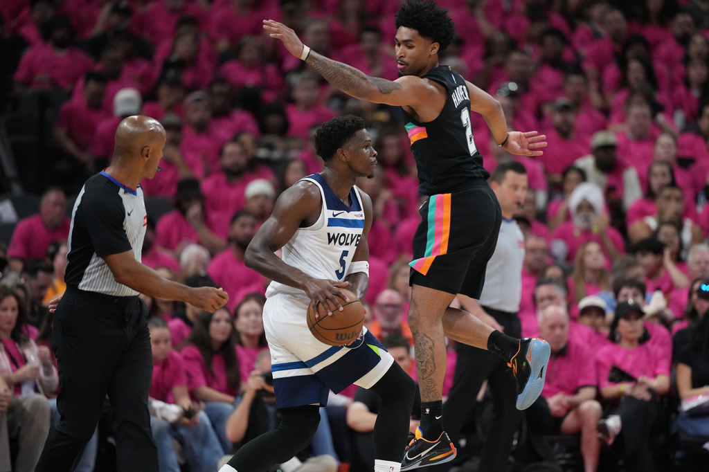 Minnesota Timberwolves guard Anthony Edwards (5) handles the ball as San Antonio Spurs guard Dylan Harper (2) defends during the first half in Game 1 of a second-round NBA playoffs basketball series in San Antonio, Monday, May 4, 2026. (AP Photo/Eric Gay)