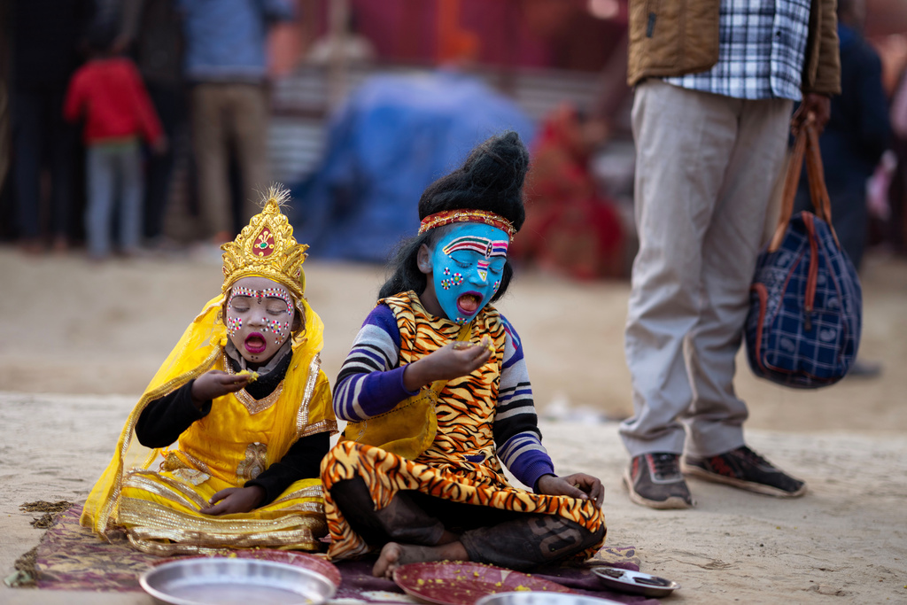 Children dressed as Hindu God Shiva, right, and Parvati eat on the side of street on the eve of Mauni Amavasya, a divine occasion in Hindu religious practice followed for honoring ancestors or forefathers, at the Sangam, the confluence of the Ganges, the Yamuna and the mythical Saraswati rivers, during the annual month long Hindu religious fair "Magh Mela" in Prayagraj, India, Saturday, Jan. 17, 2026. (AP Photo/Rajesh Kumar Singh)