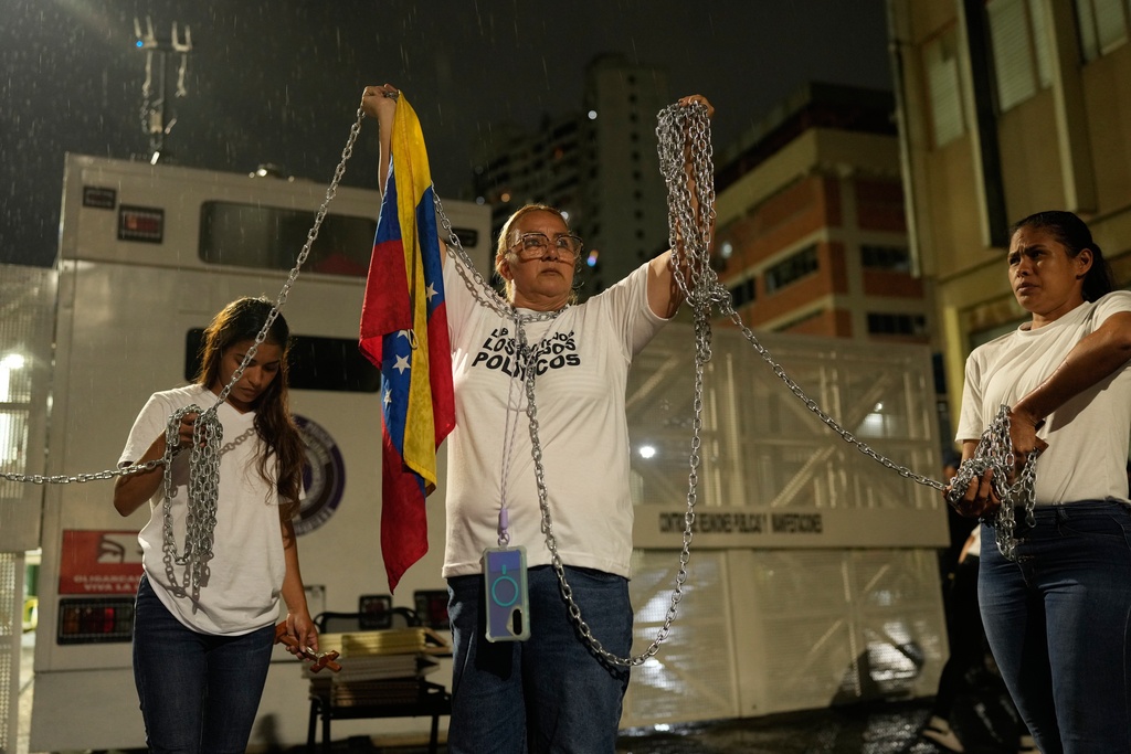 Relatives of people they consider to be detained for political reasons protest holding chains in front of police guarding the Zona 7 Bolivarian National Police detention center in Caracas, Venezuela, Friday, Jan. 30, 2026, on the same day acting President Delcy Rodríguez announced an amnesty bill that could lead to the release of hundreds of prisoners, including opposition leaders, journalists and human rights activists detained for political reasons. (AP Photo/Ariana Cubillos)