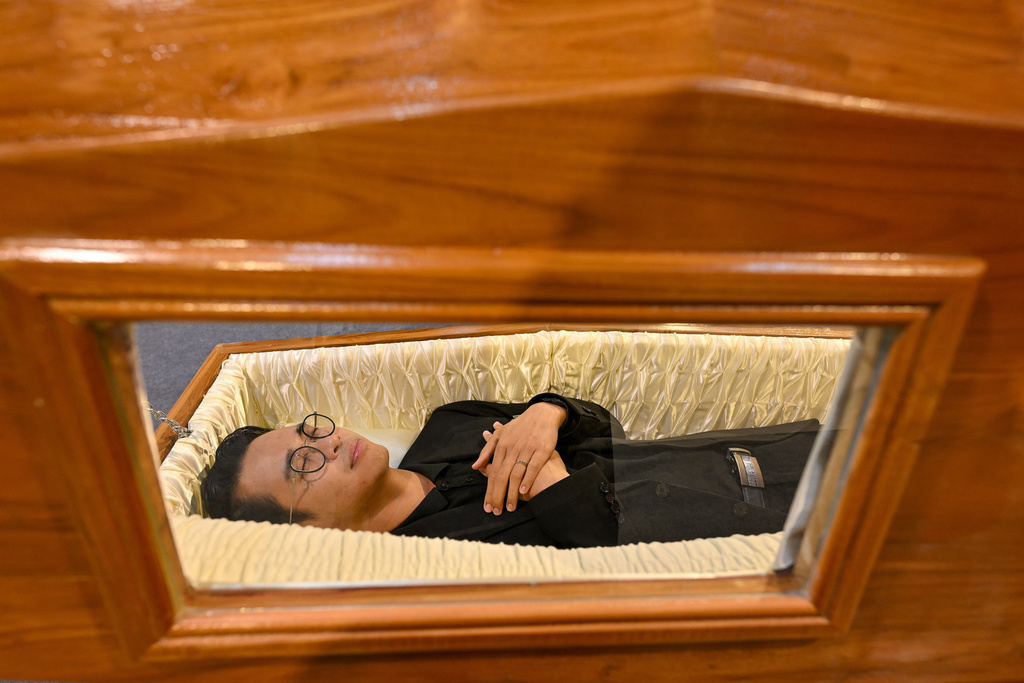 A visitor tries out a coffin at Death Fest in Nonthaburi, Thailand, Friday, March 13, 2026. (AP Photo/Kittinun Rodsupan)