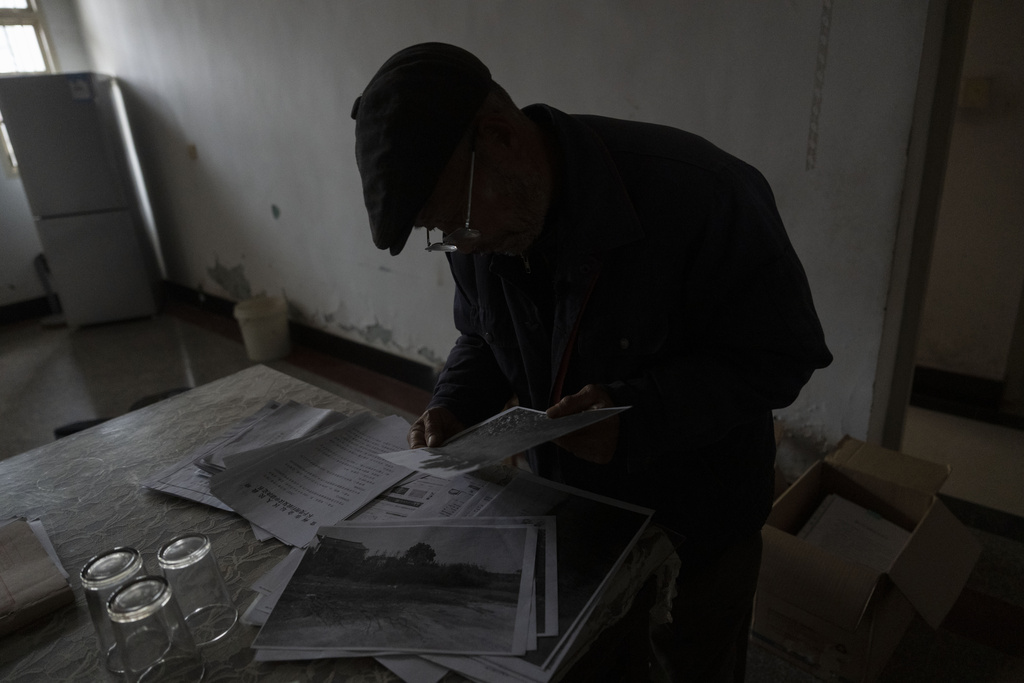Petitioner Yang Guoliang looks through documents at his home in Changzhou in eastern China's Jiangsu Province, Friday, Dec. 13, 2024. (AP Photo/Ng Han Guan)