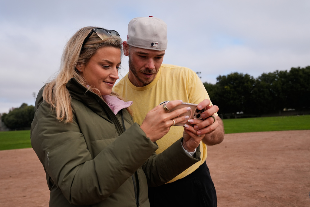 Daulton Jefferies, right, and his wife Natalie watch a video of him throwing a pitch while working out at Heather Farms Park in Walnut Creek, Calif., Saturday, Dec. 13, 2025. (AP Photo/Godofredo A. Vásquez)