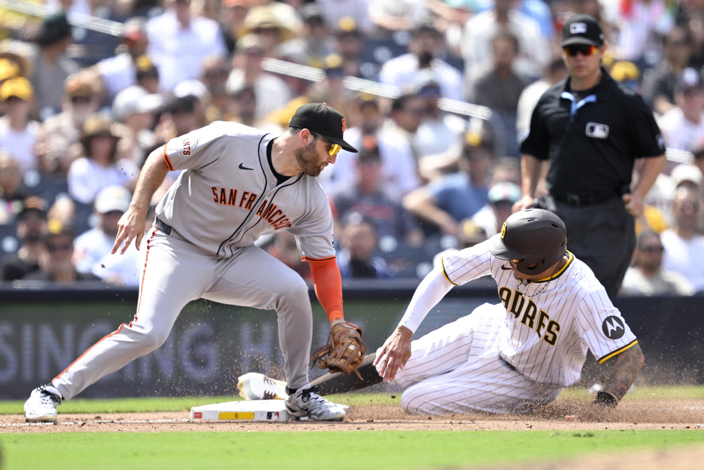 San Diego Padres' Manny Machado, front right, steals third base ahead of a tag by San Francisco Giants third baseman Casey Schmitt, left, during the fifth inning of a baseball game Thursday, Aug. 21, 2025, in San Diego. (AP Photo/Orlando Ramirez)