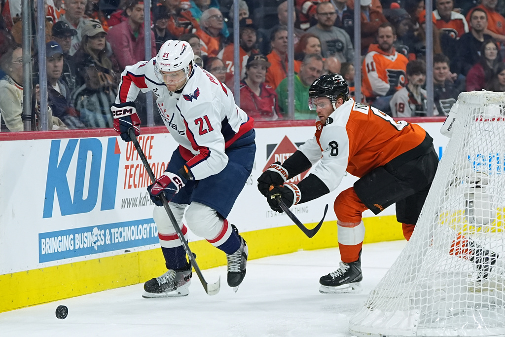 Washington Capitals' Aliaksei Protas (21) tries to keep the puck from Philadelphia Flyers' Cam York (8) during the first period of an NHL hockey game, Wednesday, March 11, 2026, in Philadelphia. (AP Photo/Matt Rourke)