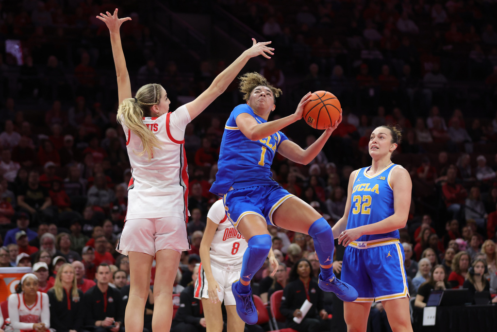 UCLA guard Kiki Rice, center, goes up to shoot between Ohio State guard Kylee Kitts, left, and forward Angela Dugalic, right, during the first half of an NCAA college basketball game in Columbus, Ohio, Sunday, Dec. 28, 2025. (AP Photo/Paul Vernon)