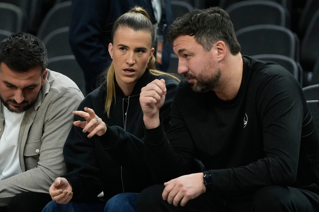 New York Liberty's Sabrina Ionescu, middle, gestures next to Liberty head coach Chris DeMarco, right, before an NBA basketball game between the Golden State Warriors and the Utah Jazz in San Francisco, Monday, Nov. 24, 2025. (AP Photo/Jeff Chiu)