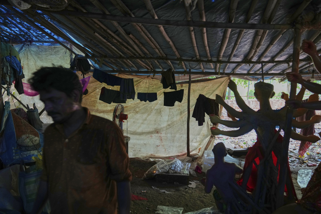 An artist walks past his living quarters in a temporary shelter where he and others are creating idols of Hindu gods and goddesses ahead of the Durga Puja festival in New Delhi, India, Saturday, Sept. 20, 2025 (AP Photo/Manish Swarup)