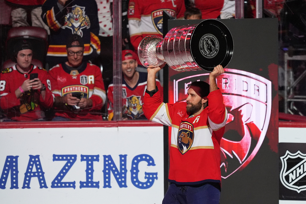 Florida Panthers defenseman Aaron Ekblad holds up the Stanley Cup as he arrives on the ice for the home opener NHL hockey game of the 2025 Stanley Cup champions, against the Chicago Blackhawks, Tuesday, Oct. 7, 2025, in Sunrise, Fla. (AP Photo/Rebecca Blackwell)