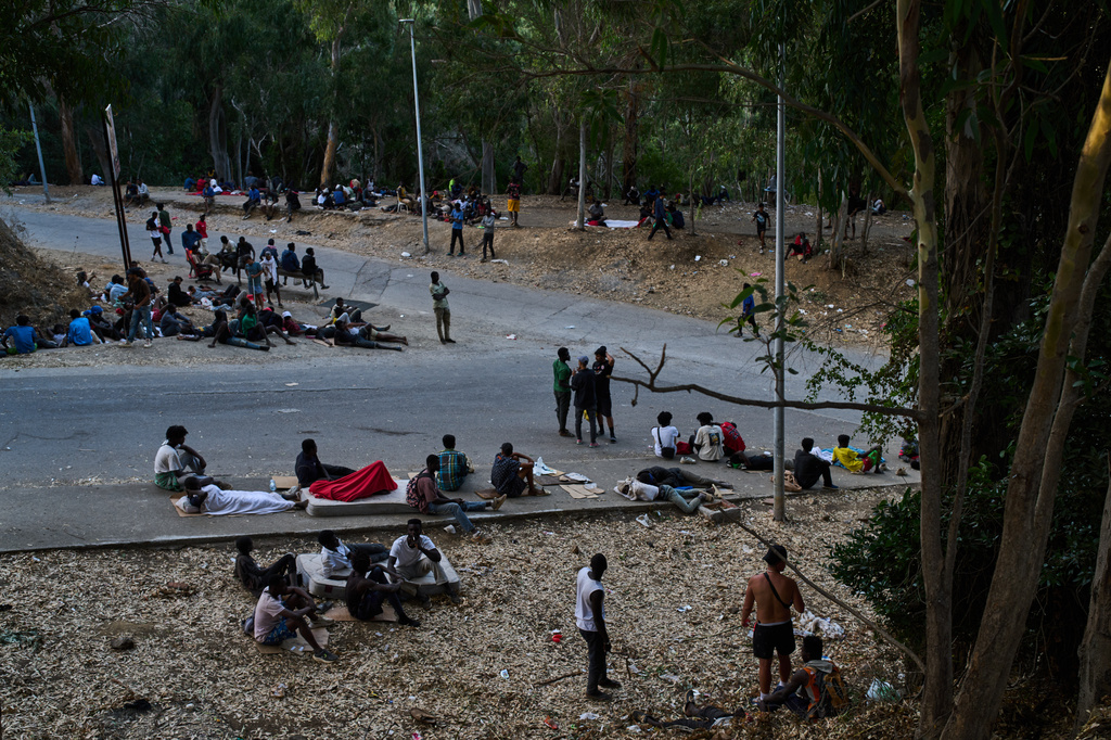 Migrants who crossed into Spain from Morocco sit outside the temporary immigrant stay center (CETI) in the Spanish enclave of Ceuta, Sunday, Aug. 2, 2026. (AP Photo/Bernat Armangue)