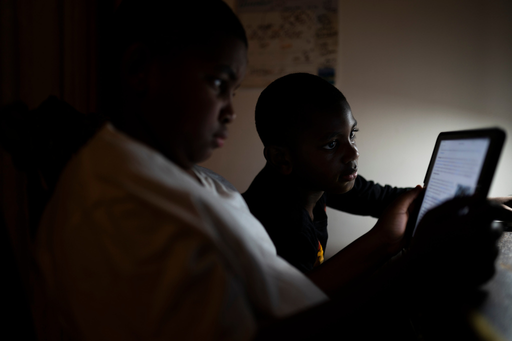 FILE - Children read on a tablet computer in their bedroom, Dec. 8, 2021, in the Brooklyn borough of New York. (AP Photo/John Minchillo, File)