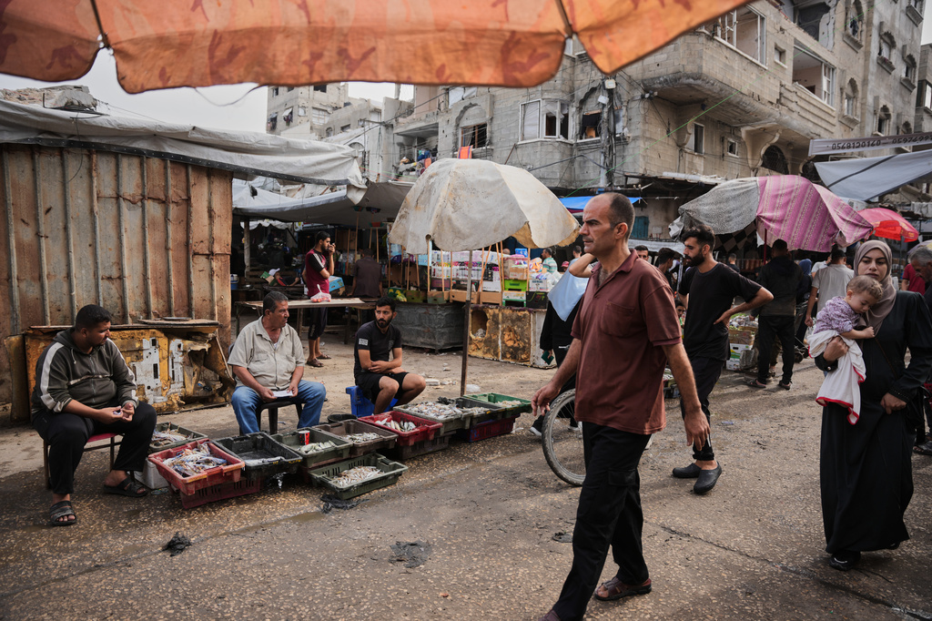Palestinians walk through a market in the Al-Shati refugee camp in Gaza City on Wednesday, Oct. 14, 2026. (AP Photo/Abdel Kareem Hana)