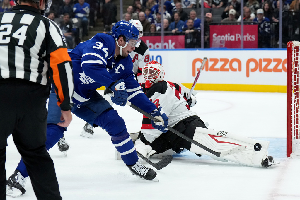 Toronto Maple Leafs centre Auston Matthews (34) misses the net as New Jersey Devils goaltender Jake Allen (34) looks on during second period NHL hockey action in Toronto, Tuesday, Oct. 21, 2025. (Nathan Denette/The Canadian Press via AP)