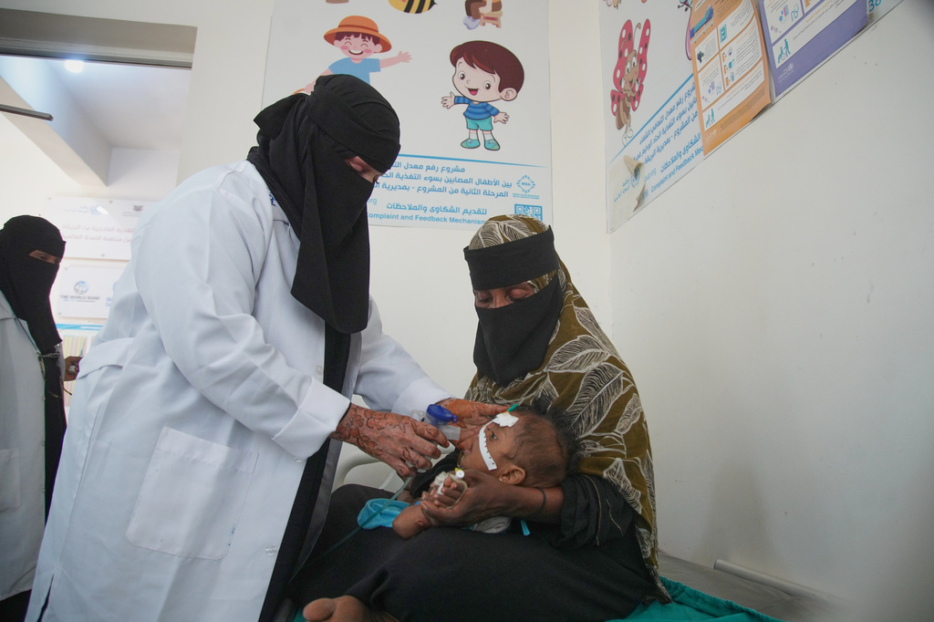 A health worker treats a child showing symptoms of malnutrition as a woman holds the child at a therapeutic feeding center in Buraiqa, on the western outskirts of Aden, Yemen, Tuesday, Sept. 22, 2026. (AP Photo/Abdulnasser Alseddik)