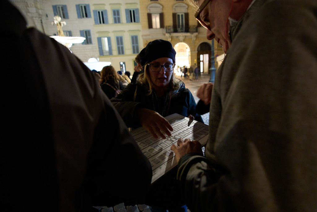Daria Portale, a guide with the Radici Association, uses a tactile panel so Enrico Sulli, right, who is blind, can experience the architecture of Palazzo Farnese during an inclusive art tour in downtown Rome, Nov. 29, 2025. (AP Photo/Alessandra Tarantino)