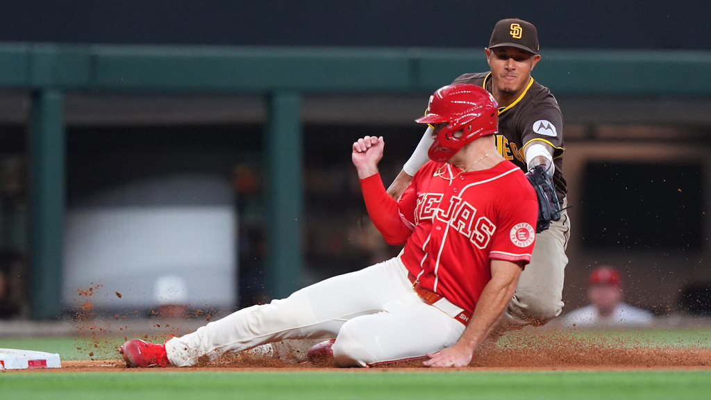 Texas Rangers' Wyatt Langford, left, is tagged out by San Diego Padres third baseman Manny Machado (13) trying to advance to third base on a single by Rangers' Brandon Nimmo during the fourth inning of a baseball game, Saturday, June 20, 2026, in Arlington, Texas. (AP Photo/LM Otero)