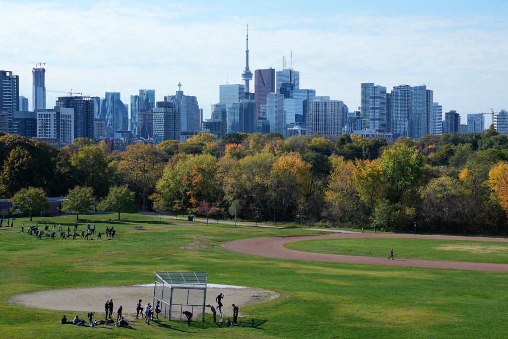 People work out with the city skyline in the background at the Riverdale Park East, in Toronto, Sunday, Nov. 2, 2025. (AP Photo/Kamran Jebreili)
