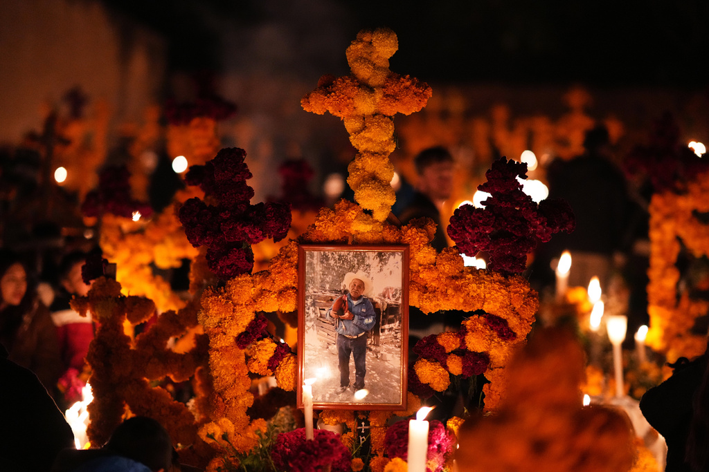 A grave is decorated with cempasuchil flowers and candles celebrating the Day of the Dead at the cemetery in Arocutin, Michoacan state, Mexico, Saturday, Nov. 1, 2025. (AP Photo/Eduardo Verdugo)