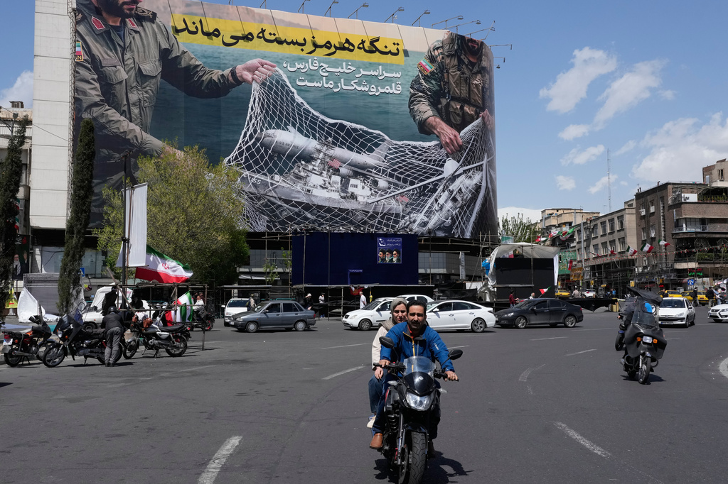 Vehicles and motorcycles move past an anti-U.S. billboard depicting the American aircrafts into the Iranian armed forces fishing net with signs that read in Farsi: "The Strait of Hormuz will remain closed, The entire Persian Gulf is our hunting ground," at the Eqelab-e-Eslami, or Islamic Revolution square in downtown Tehran, Iran, Sunday, April 5, 2026. (AP Photo/Vahid Salemi)