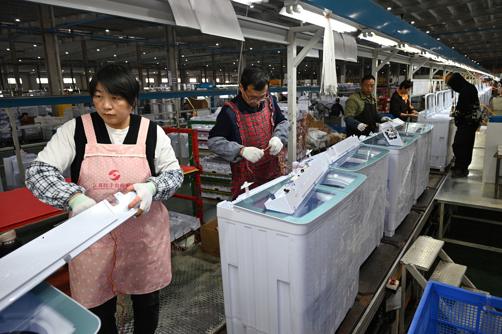 Workers install washing machines at a factory making washing machines for export, in Suqian in east China's Jiangsu province on Oct. 20, 2025. (Chinatopix Via AP)