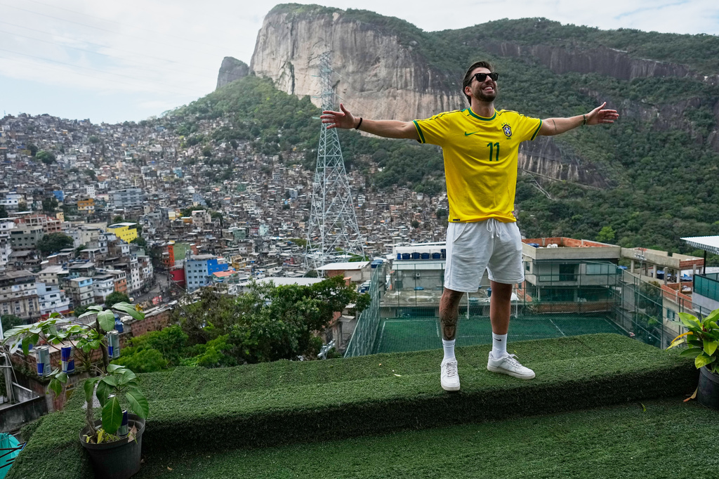 A tourist wearing a jersey in Brazilian colors poses for photos on a terrace at the Rocinha favela in Rio de Janeiro, on Sept. 2, 2026. (AP Photo/Silvia Izquierdo)