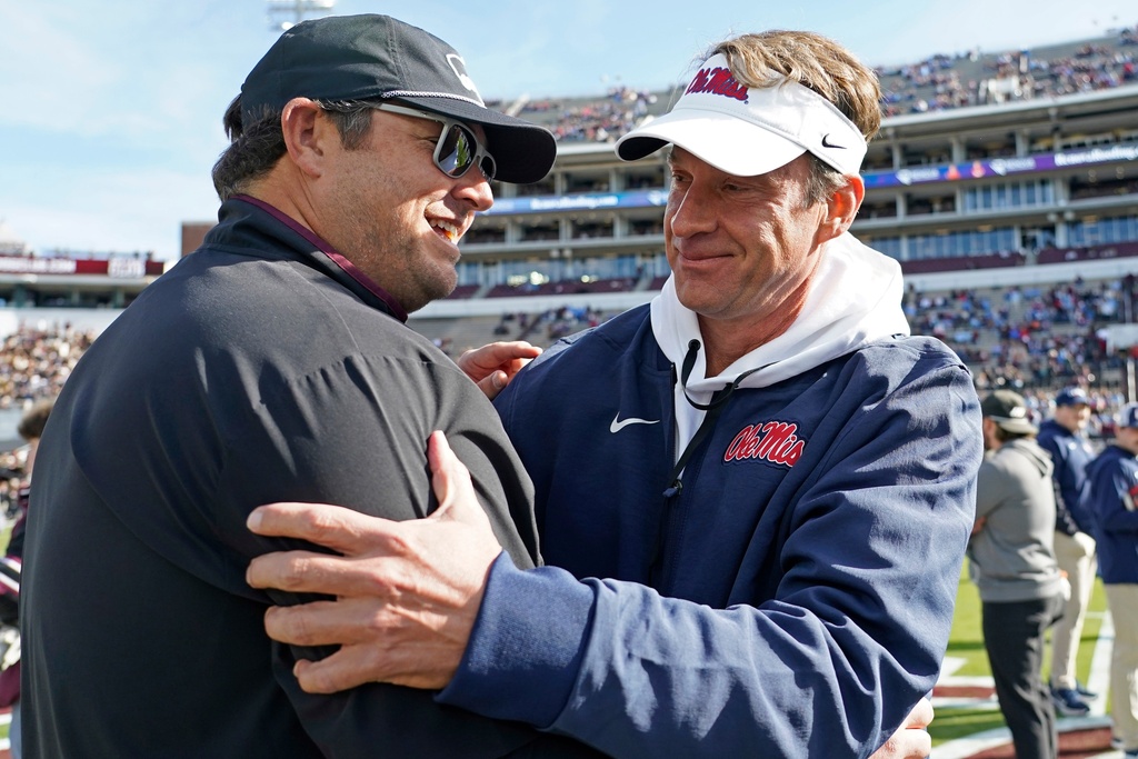 Mississippi head coach Lane Kiffin, right, greets Mississippi State head coach Jeff Lebby prior to their NCAA college football game Friday, Nov. 28, 2025, in Starkville, Miss. (AP Photo/Rogelio V. Solis)