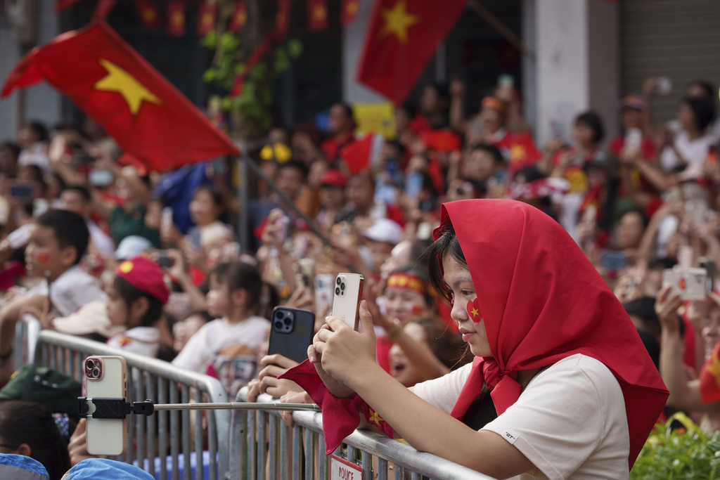 Vietnamese take picture with her mobile phone during military parade rehearsal for the Vietnam's 80th National Day celebration in old town of Hanoi, Vietnam, Saturday, Aug. 30, 2025. (AP Photo/Vincent Thian)